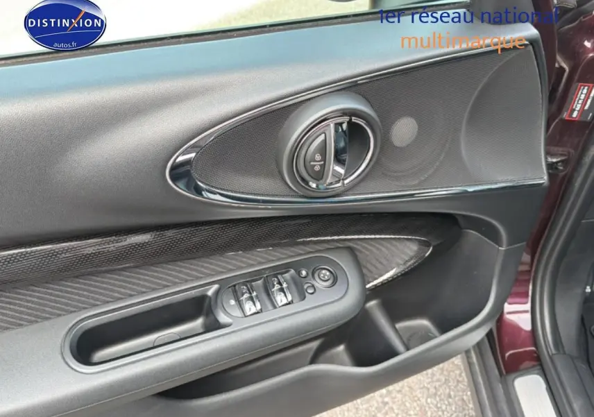 Vue rapprochée de la porte avant gauche bordeaux de la MINI Clubman F54 avec commandes électriques et insert carbone.