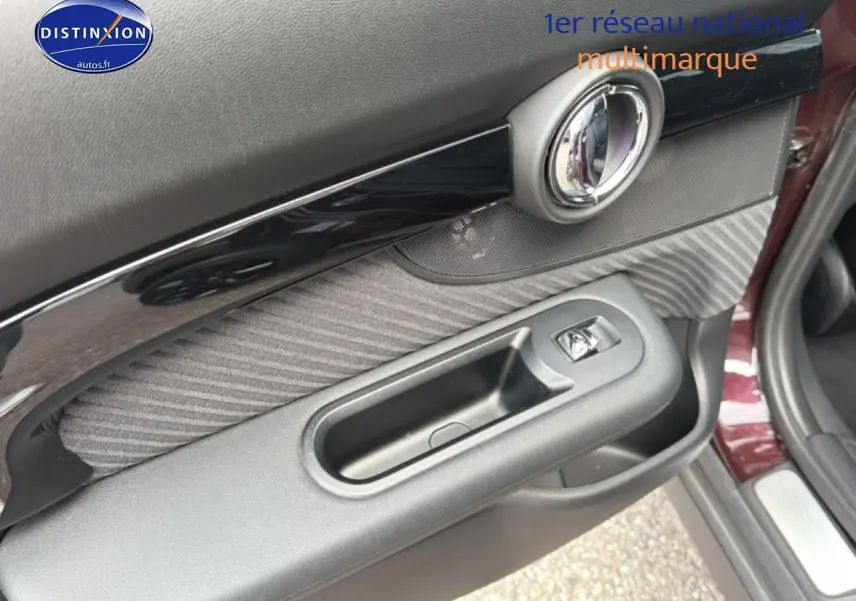 Gros plan sur la porte avant gauche bordeaux de la MINI Clubman F54, avec garniture tissu et poignée noire.