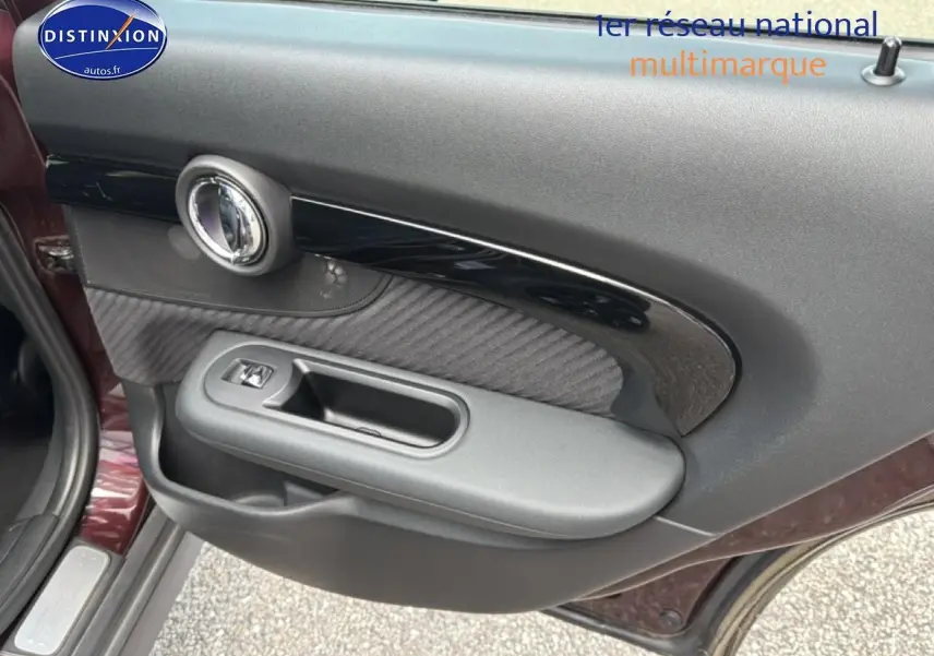 Vue rapprochée de la porte avant gauche bordeaux d'une MINI Clubman F54 avec garniture noire et poignée intégrée.