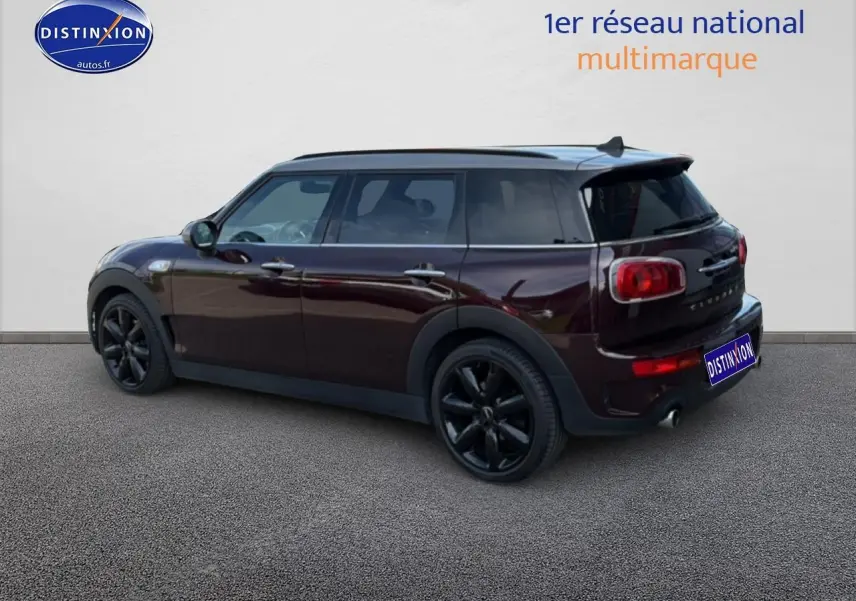 Vue 3/4 arrière droite d'une MINI Clubman bordeaux avec jantes noires et toit panoramique en verre.