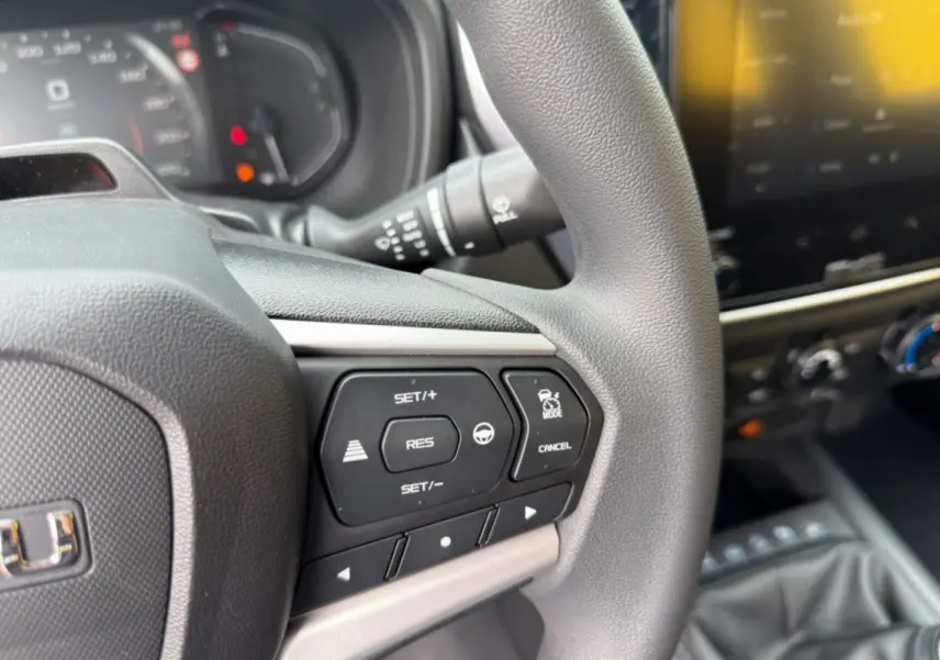 Gros plan sur le volant multifonctions gris d’un Isuzu D-MAX 2026 avec commandes de régulateur et tableau de bord flou.