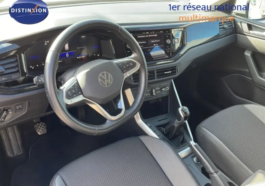 Vue intérieure du poste de conduite du Volkswagen Taigo 2022, volant multifonction et levier de vitesses manuel visibles.