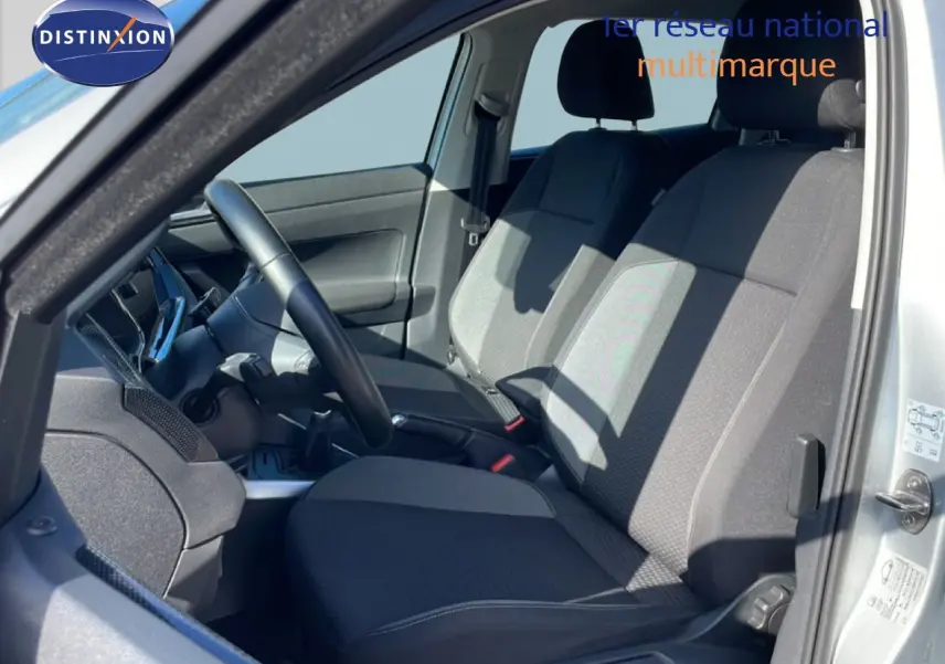 Vue intérieure côté conducteur du Volkswagen Taigo 2022 en reflet d'argent, sièges tissu gris et volant cuir noir.