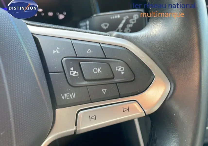 Gros plan sur les commandes multifonctions en plastique noir et argent du volant cuir noir d’un Volkswagen Taigo 2022.