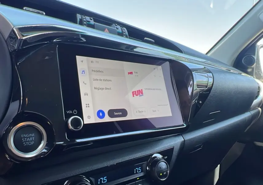 Vue intérieure côté passager du tableau de bord du Toyota Hilux gris atlas, avec écran tactile et bouton start/stop visibles.
