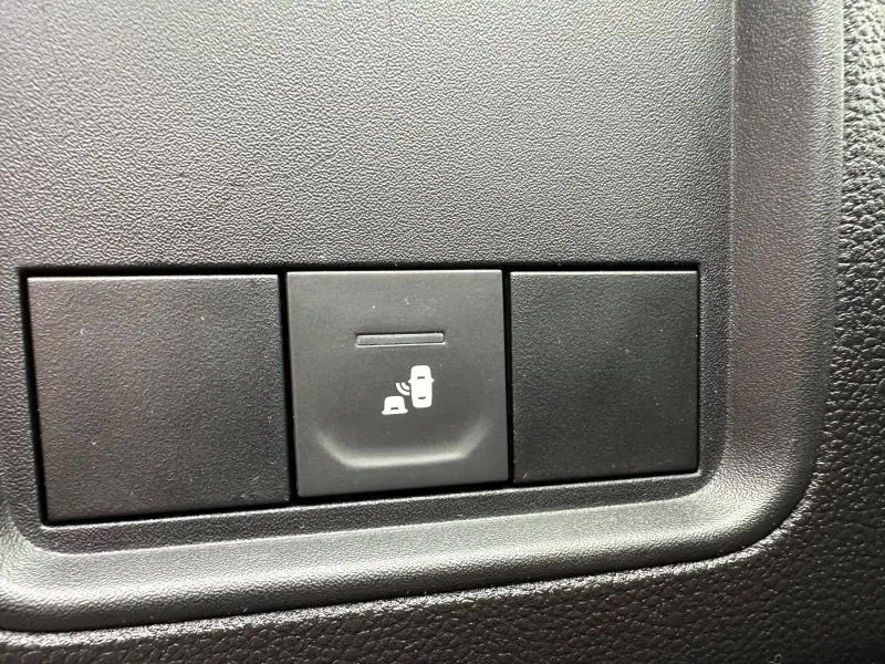 Bouton de commande du système de contrôle des angles morts sur tableau de bord noir du Dacia Duster blanc 2024