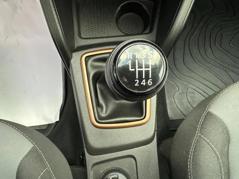 Le levier de vitesses manuel noir du Dacia Duster 2024, vu de dessus, entouré d'un cadre beige cuivré.
