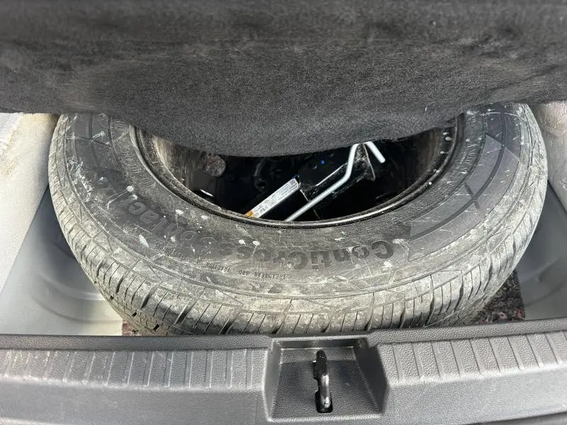 Roue de secours et cric visibles dans le coffre du Dacia Duster blanc 2024, vue plongeante depuis l'arrière.