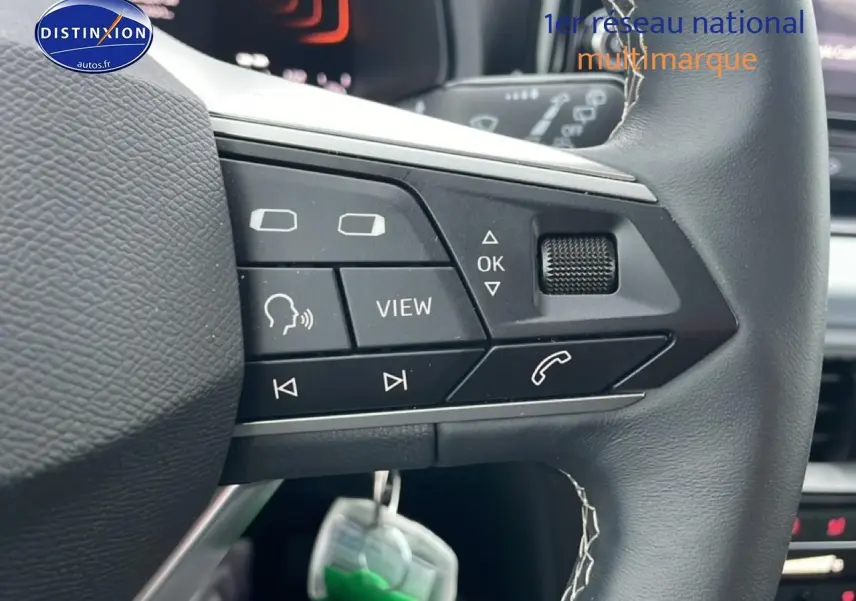 Gros plan sur les commandes noires multifonctions du volant cuir méplat d'une SEAT Arona blanc Nevada 2025.