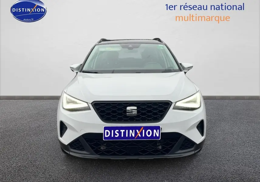 Vue avant d'un SEAT Arona blanc Nevada avec calandre noire et projecteurs full LED allumés.