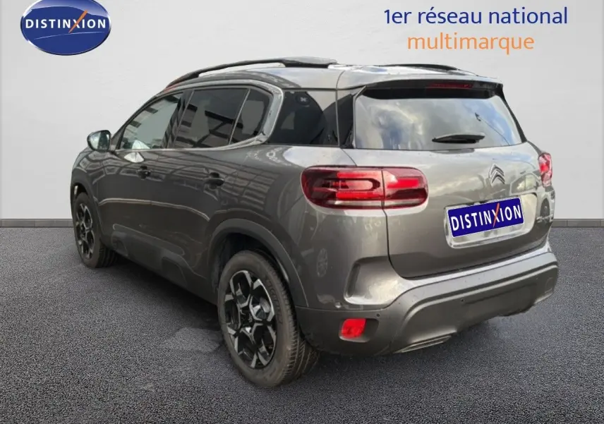 Vue 3/4 arrière droite d’un Citroën C5 Aircross gris platinium métal avec jantes noires et toit panoramique.