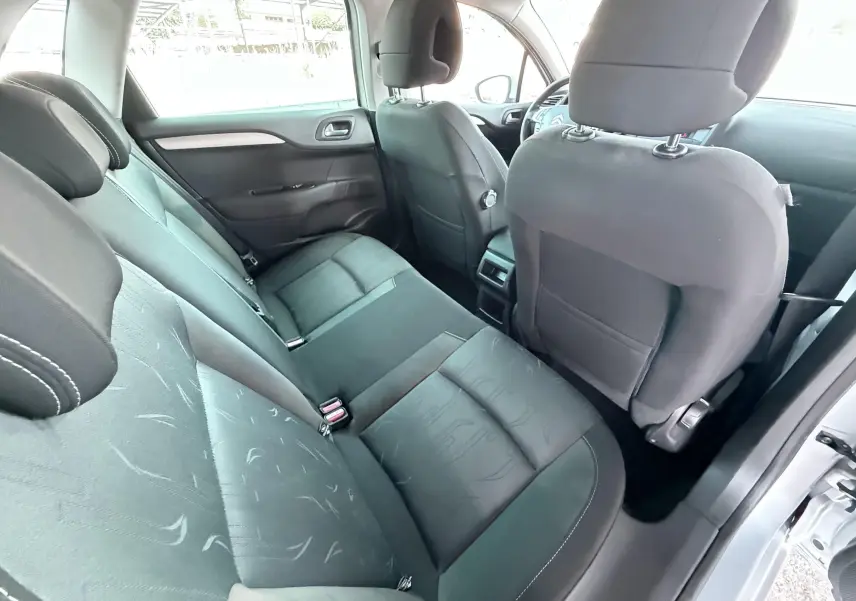 Vue intérieure arrière côté droit de la Citroën C4 gris, montrant les sièges tissu noir et l'espace passagers.