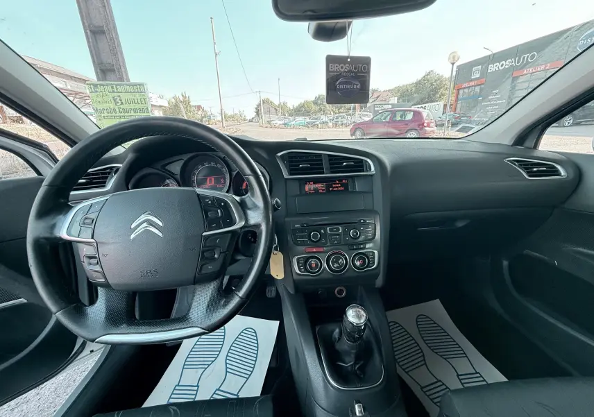 Vue intérieure avant de la Citroën C4 1.6 HDI gris, volant multifonction et levier de vitesses manuel visibles.