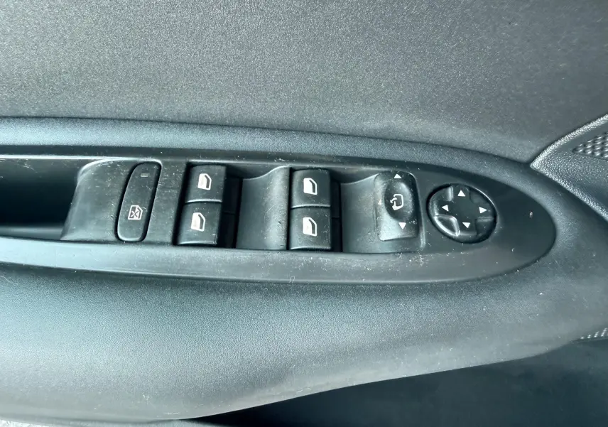 Vue rapprochée des commandes de lève-vitres et réglage des rétroviseurs côté conducteur d'une Citroën C4 gris.