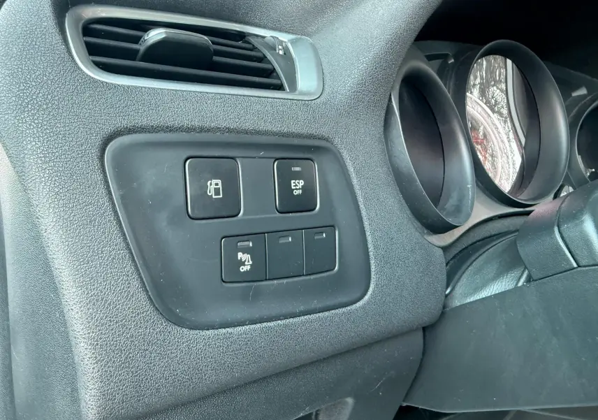 Détail du tableau de bord côté gauche de la Citroën C4 gris, avec commandes ESP et ouverture du réservoir.