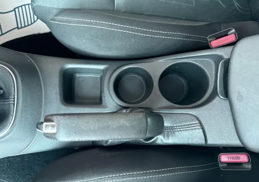 Vue plongeante sur la console centrale intérieure noire de la Citroën C4 avec frein à main et porte-gobelets.