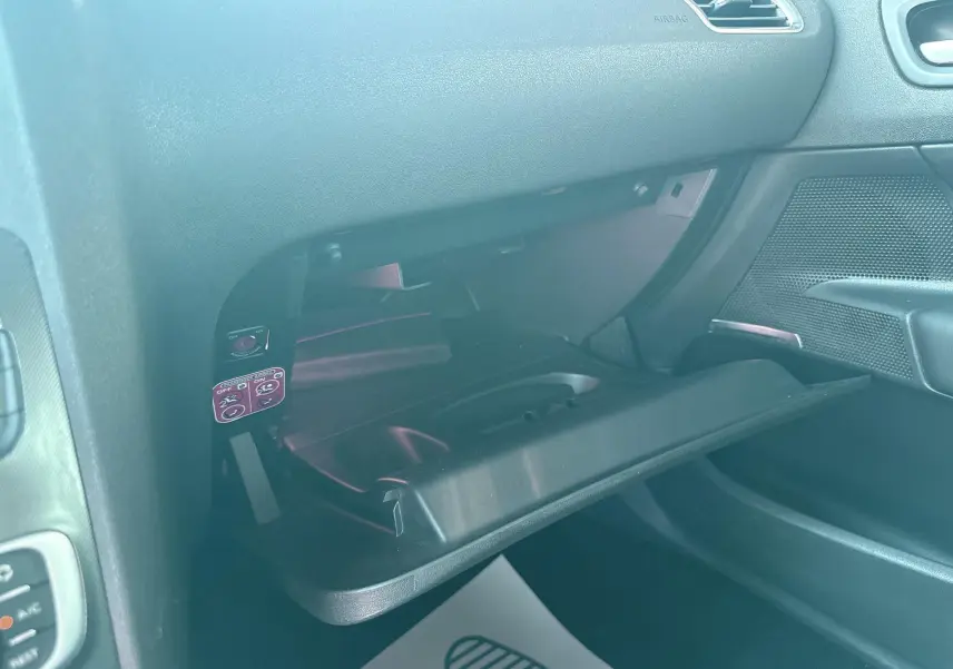 Intérieur noir de la Citroën C4 2011, vue du coffre à gants ouvert côté passager.