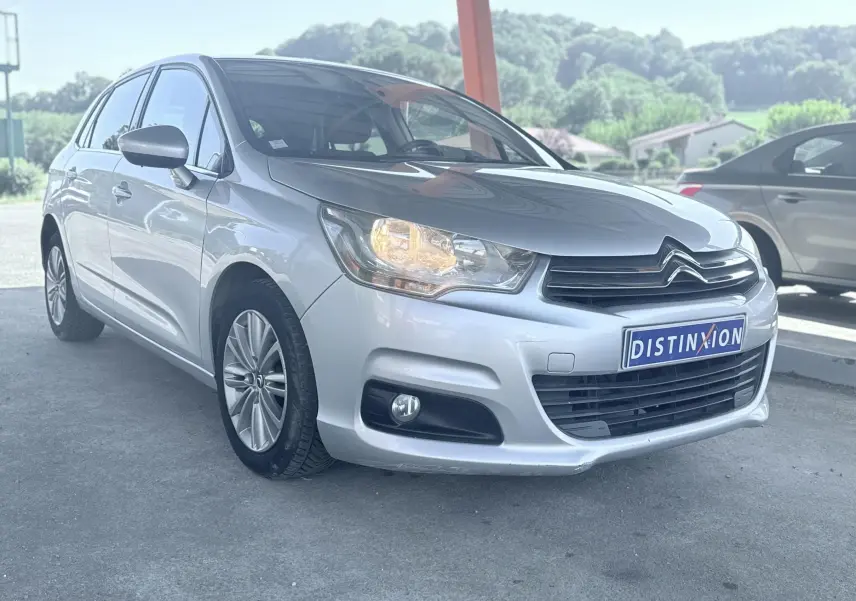 Citroën C4 gris vue 3/4 avant droit avec phare allumé, calandre noire et jantes alliage 16 pouces.