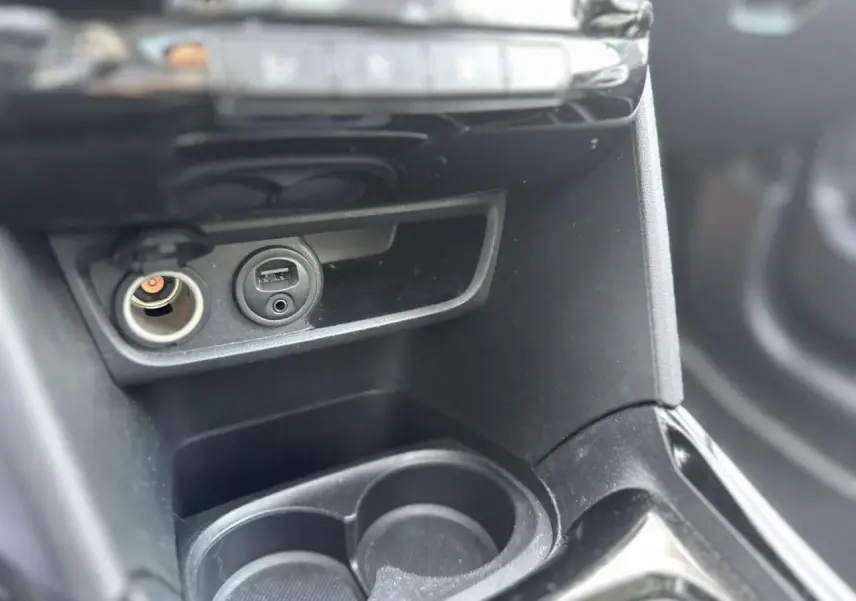 Gros plan sur la console centrale intérieure du Peugeot 2008 gris foncé, montrant prises USB et allume-cigare.