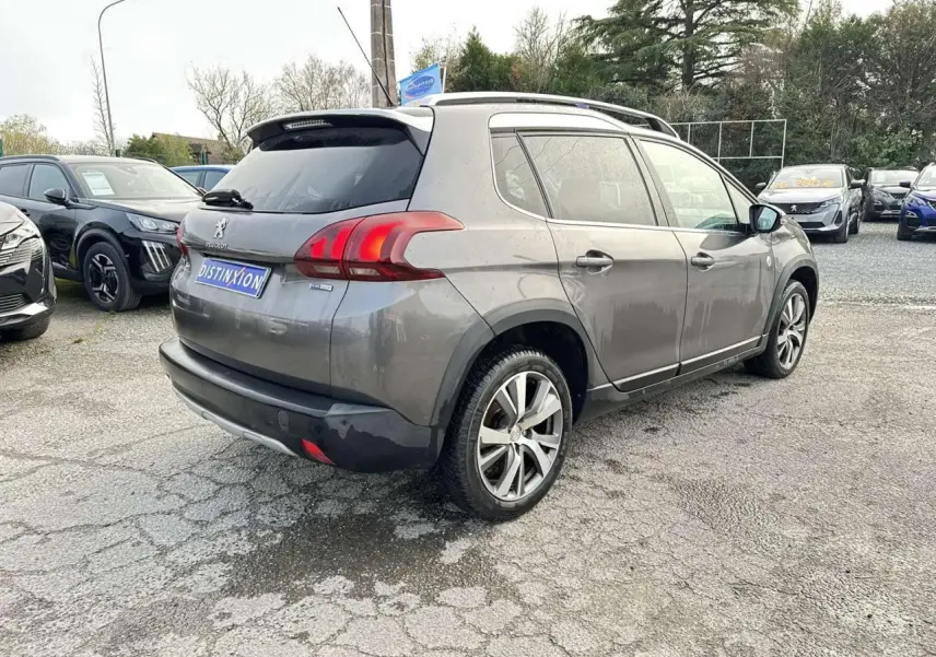 Peugeot 2008 gris foncé vue 3/4 arrière droit, avec jantes aluminium 17'' et coques de rétroviseurs chrome brillant.