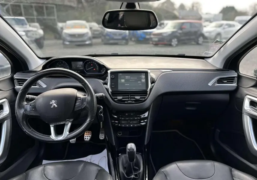 Vue frontale de l'habitacle du Peugeot 2008 gris foncé, avec volant cuir multifonction et écran tactile central.