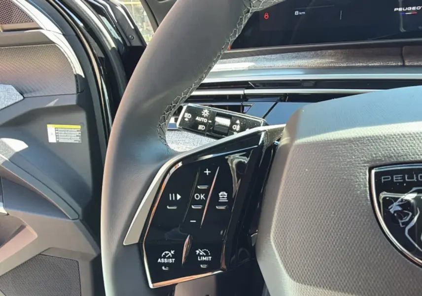 Gros plan sur le volant cuir multifonctions de la Peugeot 5008 noir perla nera, avec commandes d'assistance et régulateur.