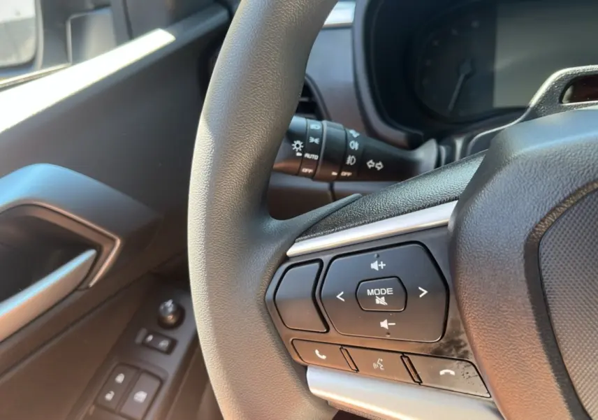 Gros plan sur le volant multifonctions noir et la portière côté gauche avec commandes électriques du Isuzu D-MAX 2026.