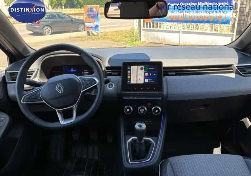 Vue intérieure frontale du tableau de bord de la Renault Clio 2025, volant multifonction et écran tactile central.