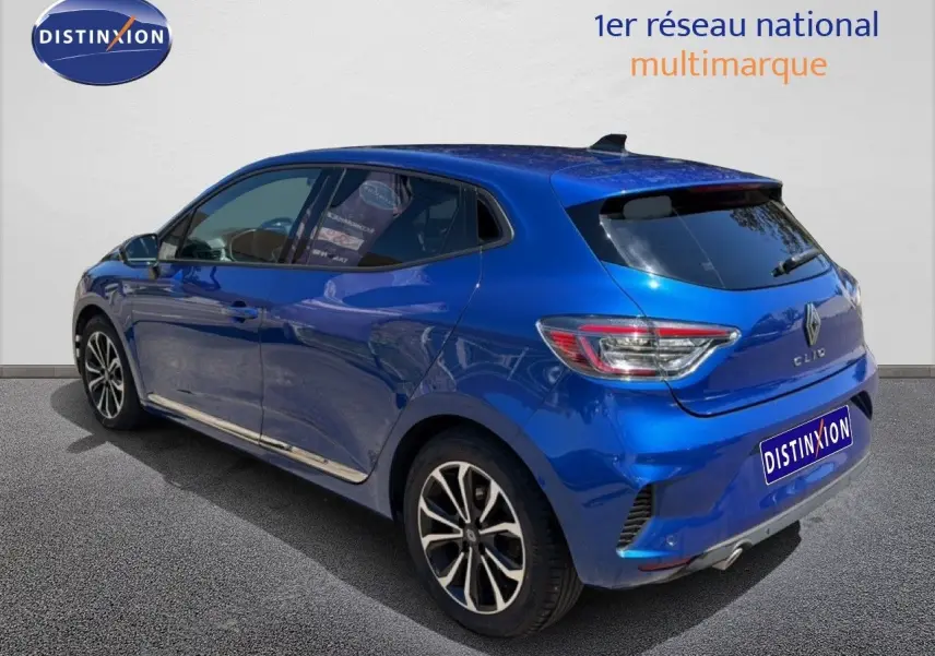 Renault Clio bleu iron metal en 3/4 arrière droit, avec jantes alliage et vitres teintées.