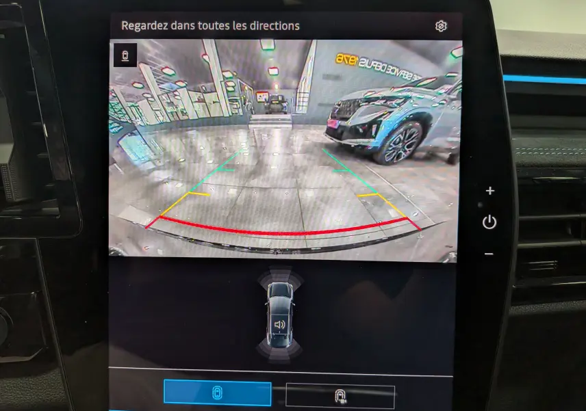 Vue caméra de recul montrant une Renault Rafale noir étoilé garée en intérieur avec lignes de guidage colorées.