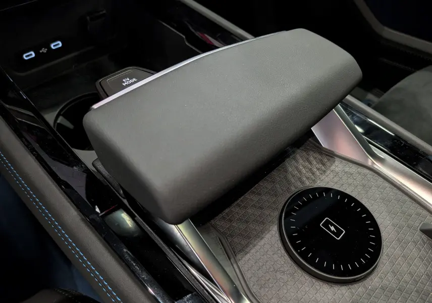 Gros plan sur la console centrale noire étoilée du Renault Rafale hybride, avec accoudoir et chargeur sans fil visible.