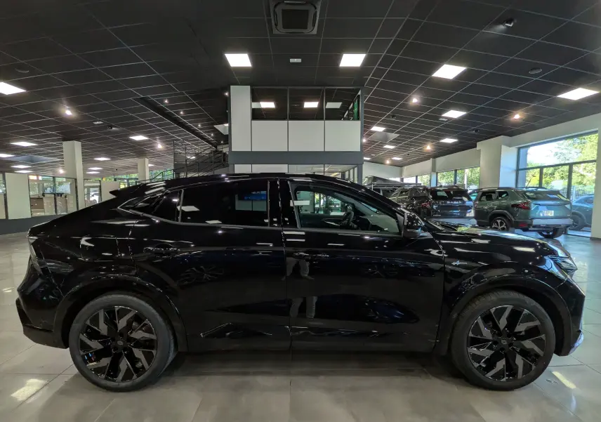 Vue de profil côté gauche d’un Renault Rafale noir étoilé, soulignant ses jantes noires et son design sportif en showroom.
