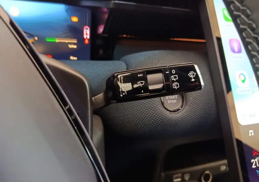 Gros plan sur la commande d’essuie-glace noire et le bouton start/stop dans l’habitacle sombre du Citroën C5 Hybride 2026.