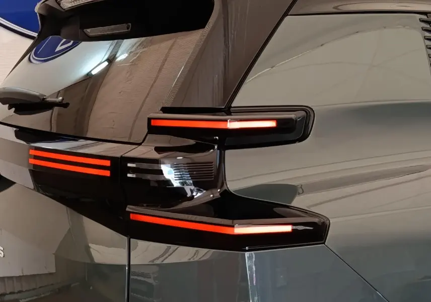 Feu arrière droit allumé d'une Citroën C5 hybride 2026 vert, vue en gros plan sur le hayon et la lunette arrière.