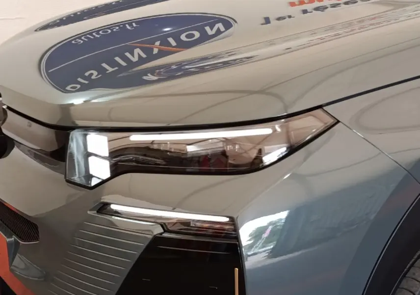 Gros plan sur l'avant droit vert métallisé du Citroën C5 Hybride 145ch avec phares LED et calandre distinctive.