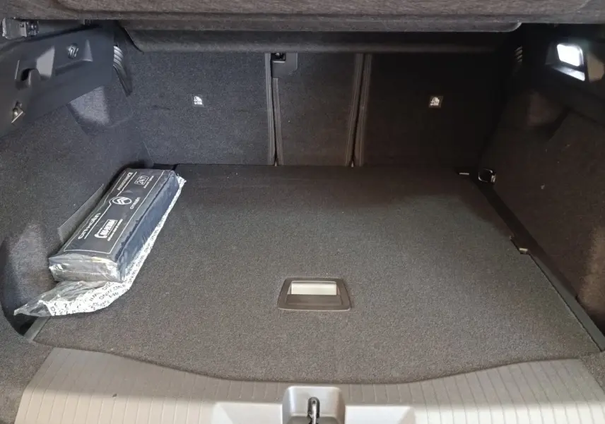 Coffre spacieux de Citroën C5 Hybride 2026 vu de face, revêtement noir avec kit de sécurité sur le côté gauche.
