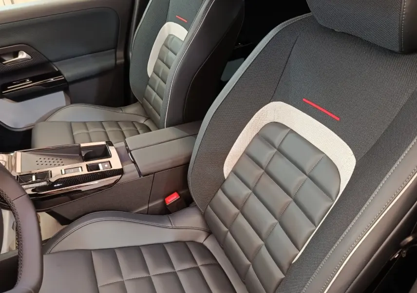 Vue intérieure rapprochée des sièges avant en cuir noir et tissu gris avec surpiqûres rouges d'une Citroën C5 Hybride.
