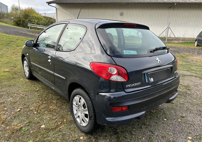 Peugeot 206+ gris foncé vue en 3/4 arrière côté gauche, avec feux arrière rouges et jantes alliage.