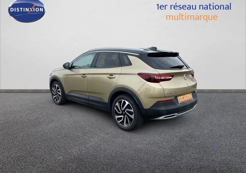 Opel Grandland X diesel doré vue 3/4 arrière droit avec toit noir et jantes bi-ton sur fond neutre.