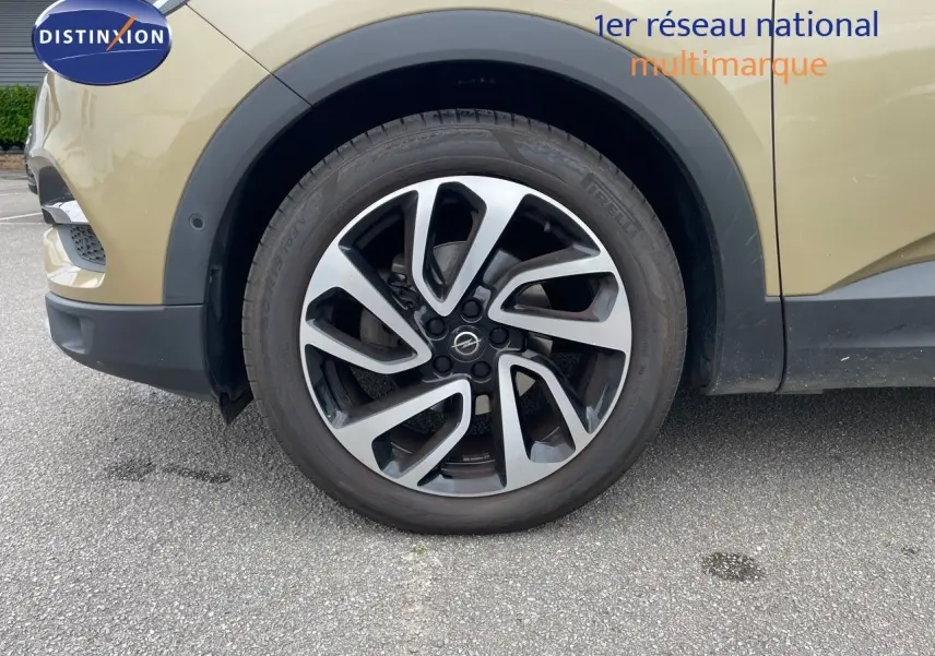 Gros plan sur la roue avant gauche d'un Opel Grandland X 2018 couleur Golden Sunstone Metal avec jante alu bicolore.