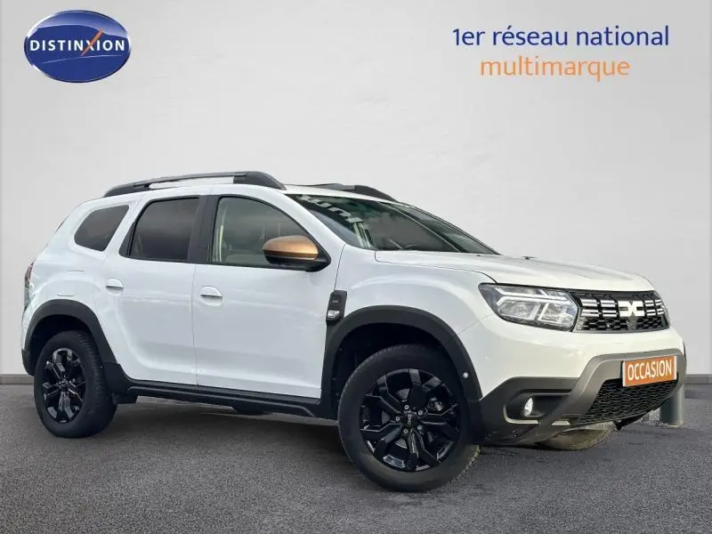 Vue 3/4 avant droite d'un Dacia Duster blanc Glacier avec jantes noires et coques de rétroviseurs bronze.