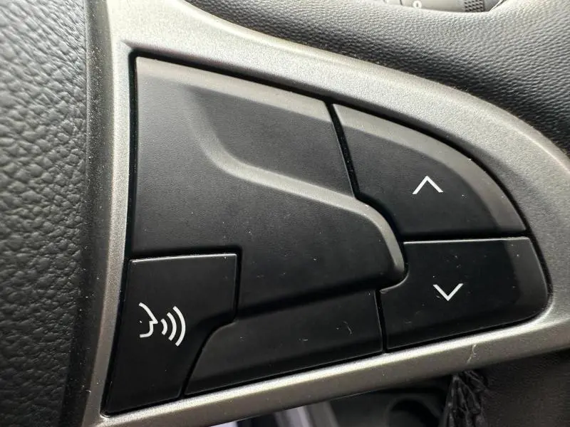 Boutons de commande vocales et de navigation sur le volant noir du Dacia Duster 2024, version Extreme 1.5 Blue dCi blanc.