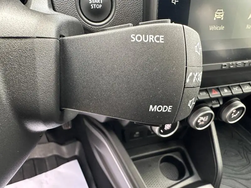Gros plan sur la commande au volant du Dacia Duster 2024, version 1.5 Blue dCi 115ch Extreme, avec boutons Source et Mode.