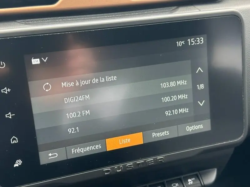 Écran tactile central du tableau de bord du Dacia Duster 2024 affichant la liste des stations radio FM.