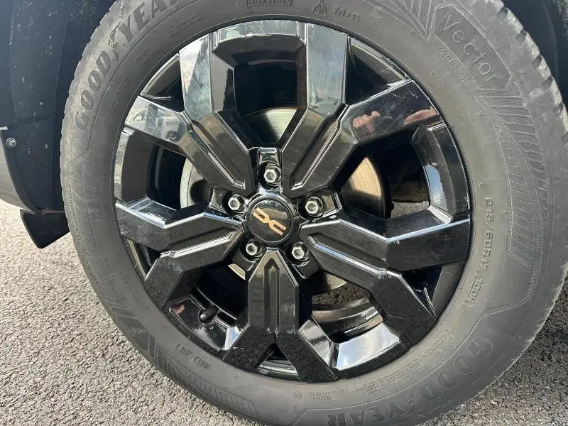 Gros plan sur la jante noire brillante du Dacia Duster 2024 blanc glacier, mettant en valeur le logo central et le pneu Goodyear.