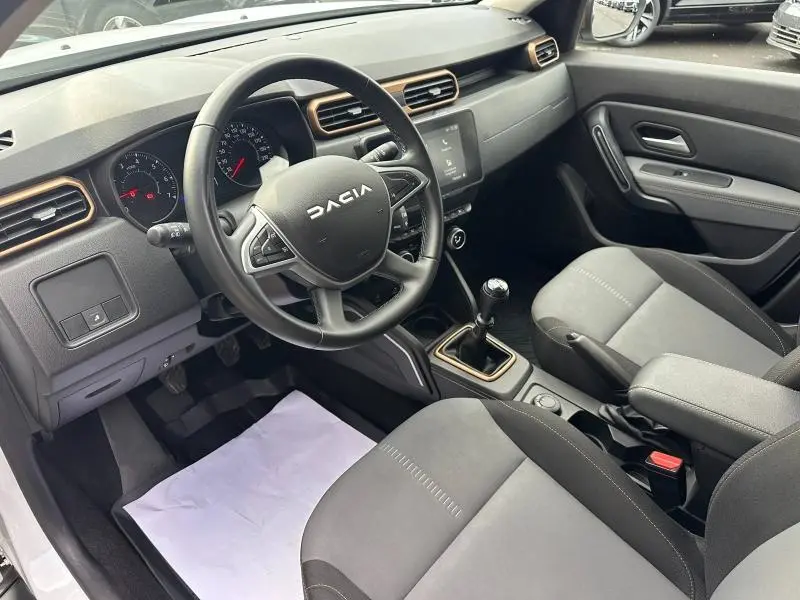 Vue intérieure côté conducteur du Dacia Duster 2024, tableau de bord noir avec touches bronze et volant multifonction.