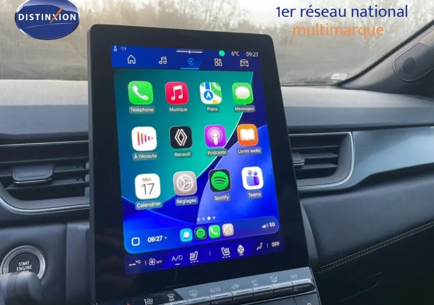 Vue intérieure centrée sur l'écran tactile vertical du tableau de bord du Renault Symbioz gris Cassiopée, avec commandes climatisation visibles.
