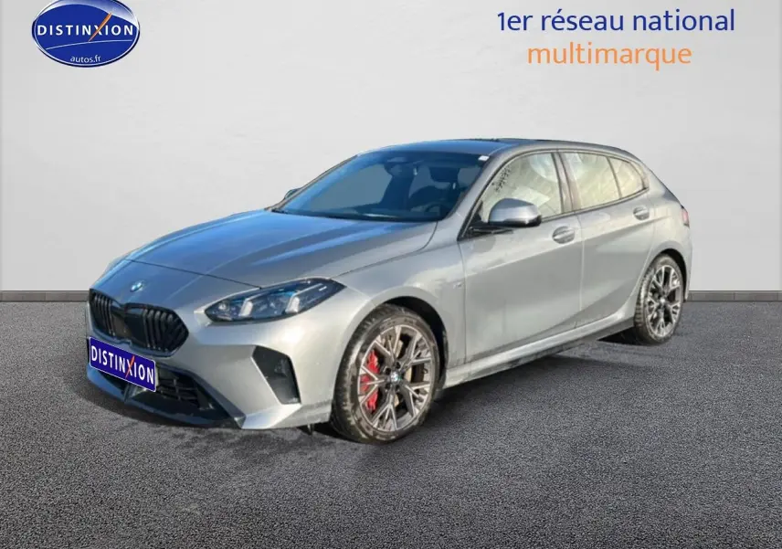 BMW Série 1 118da gris skyscraper vue 3/4 avant droit avec jantes bicolores et étriers rouges visibles.