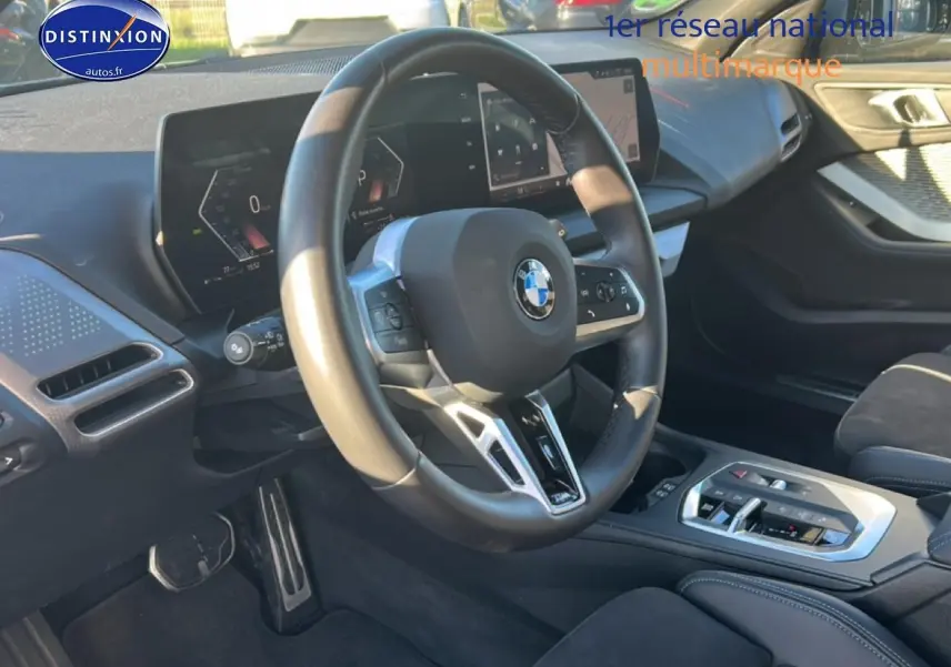 Vue intérieure centrée sur le volant et le tableau de bord numérique de la BMW Série 1 gris Skyscraper.