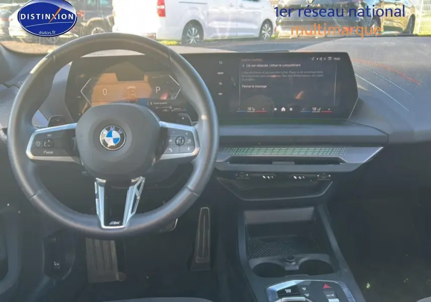 Vue intérieure frontale du tableau de bord et volant de la BMW Série 1 gris Skyscraper avec écran tactile et finitions modernes.